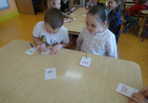 Dzieci liczą elementy i zaznaczają klamerką właściwą cyfrę na swojej karcie.